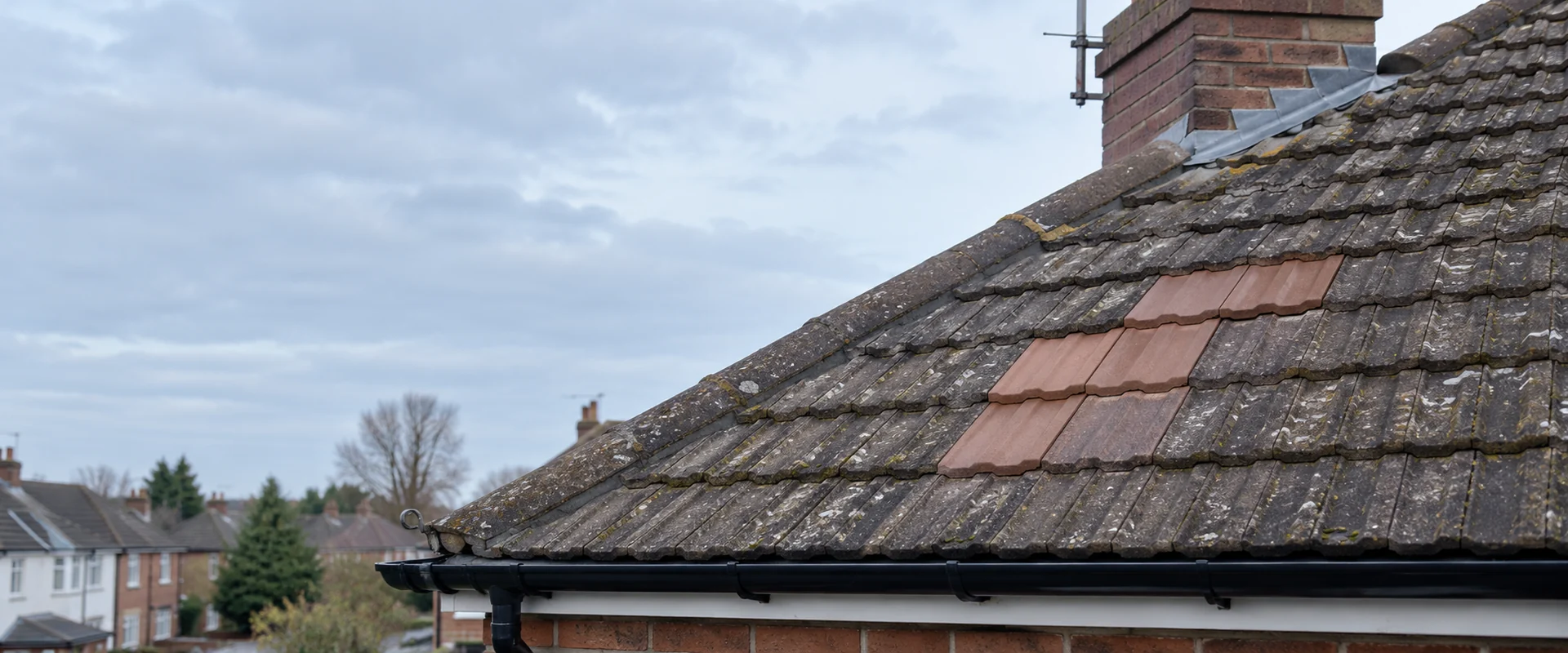 Illustrative weathered tiled roof with a repaired section.